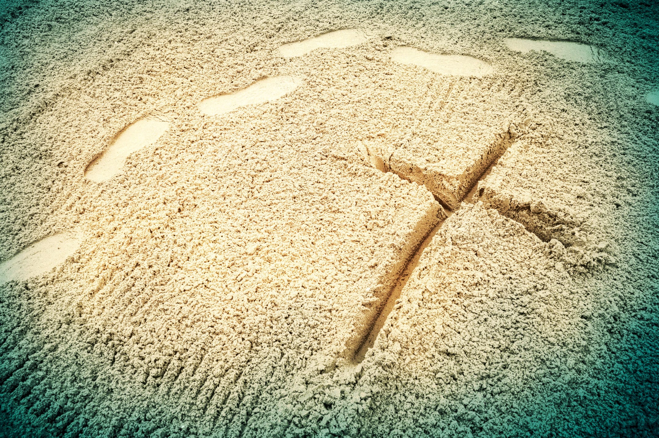 Footsteps near a cross made in the sand