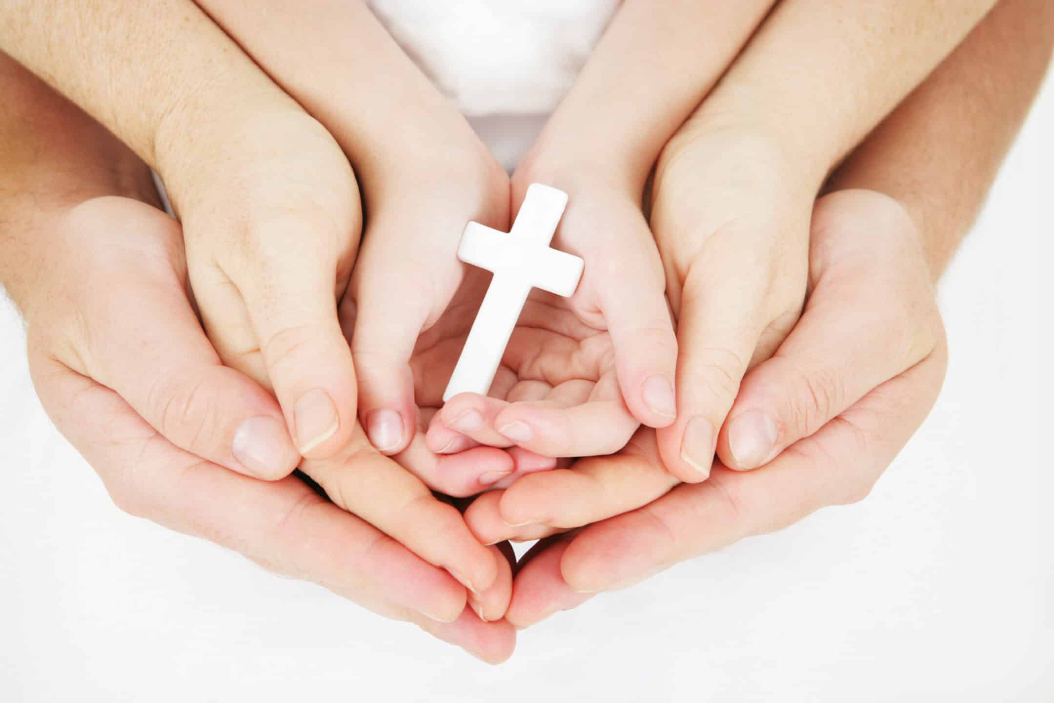 Family Hands holding a white cross