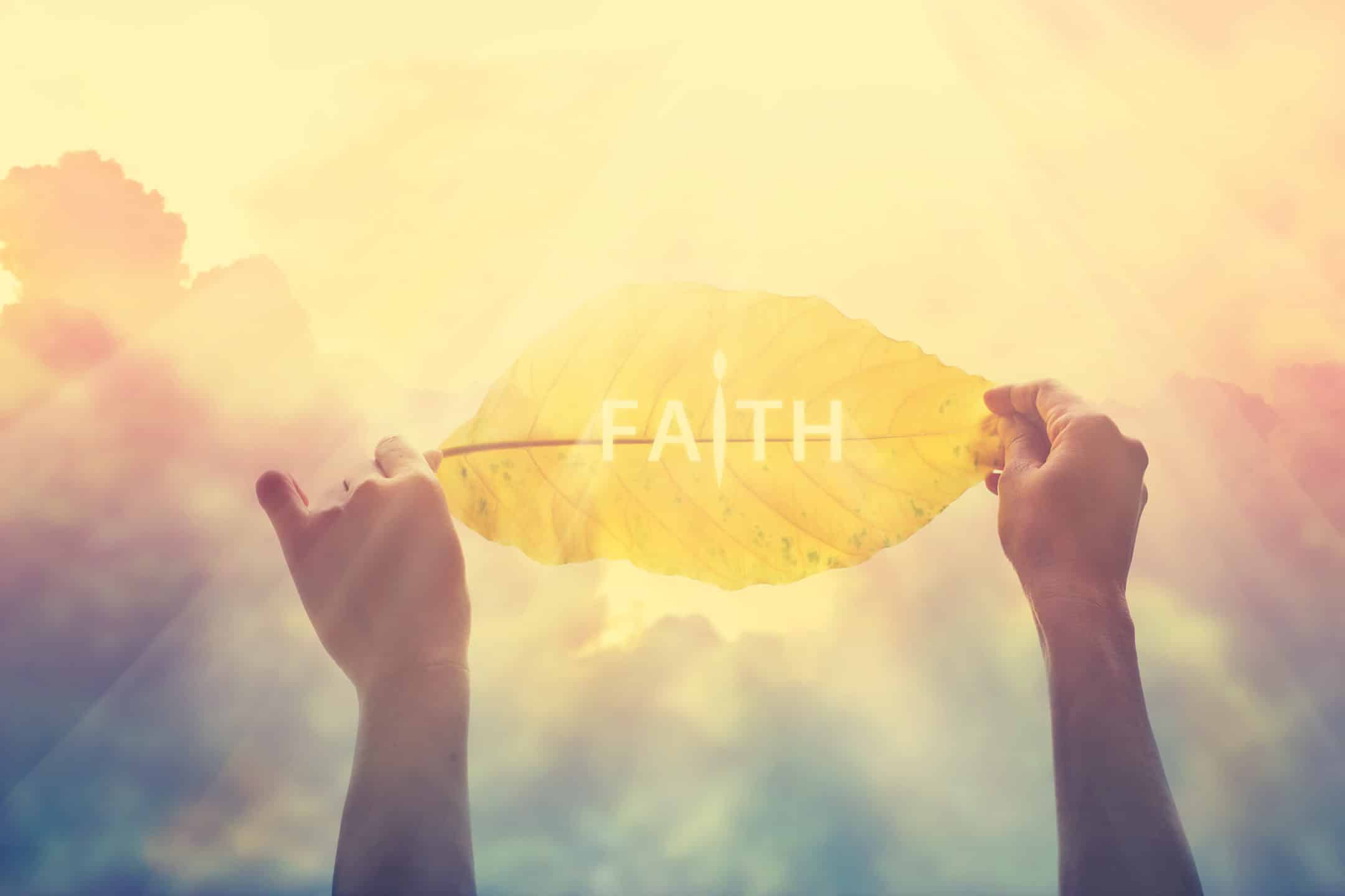 Holding up a Yellow Leaf with the words 'Faith'