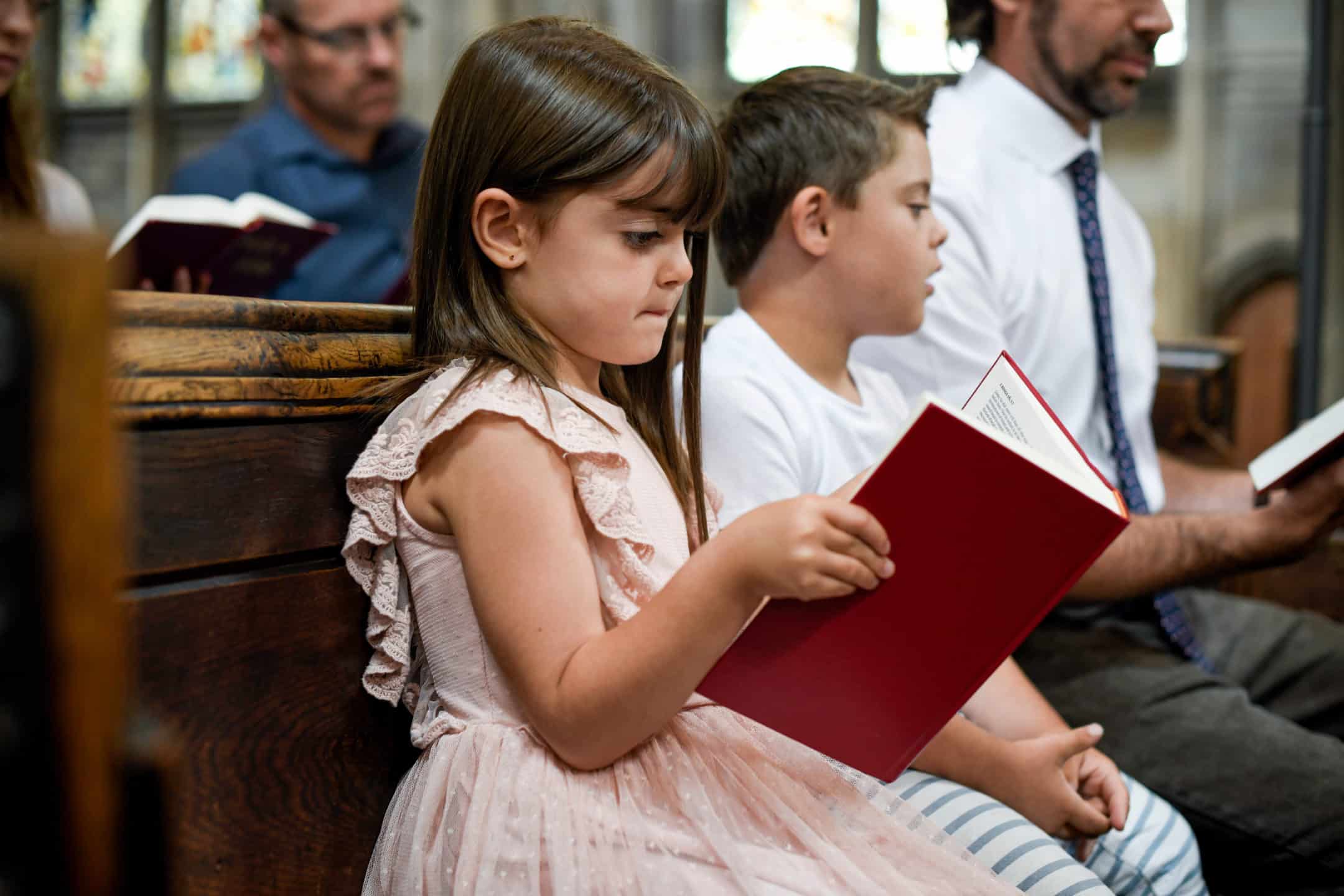 kids sitting in a church pew reading a prayer