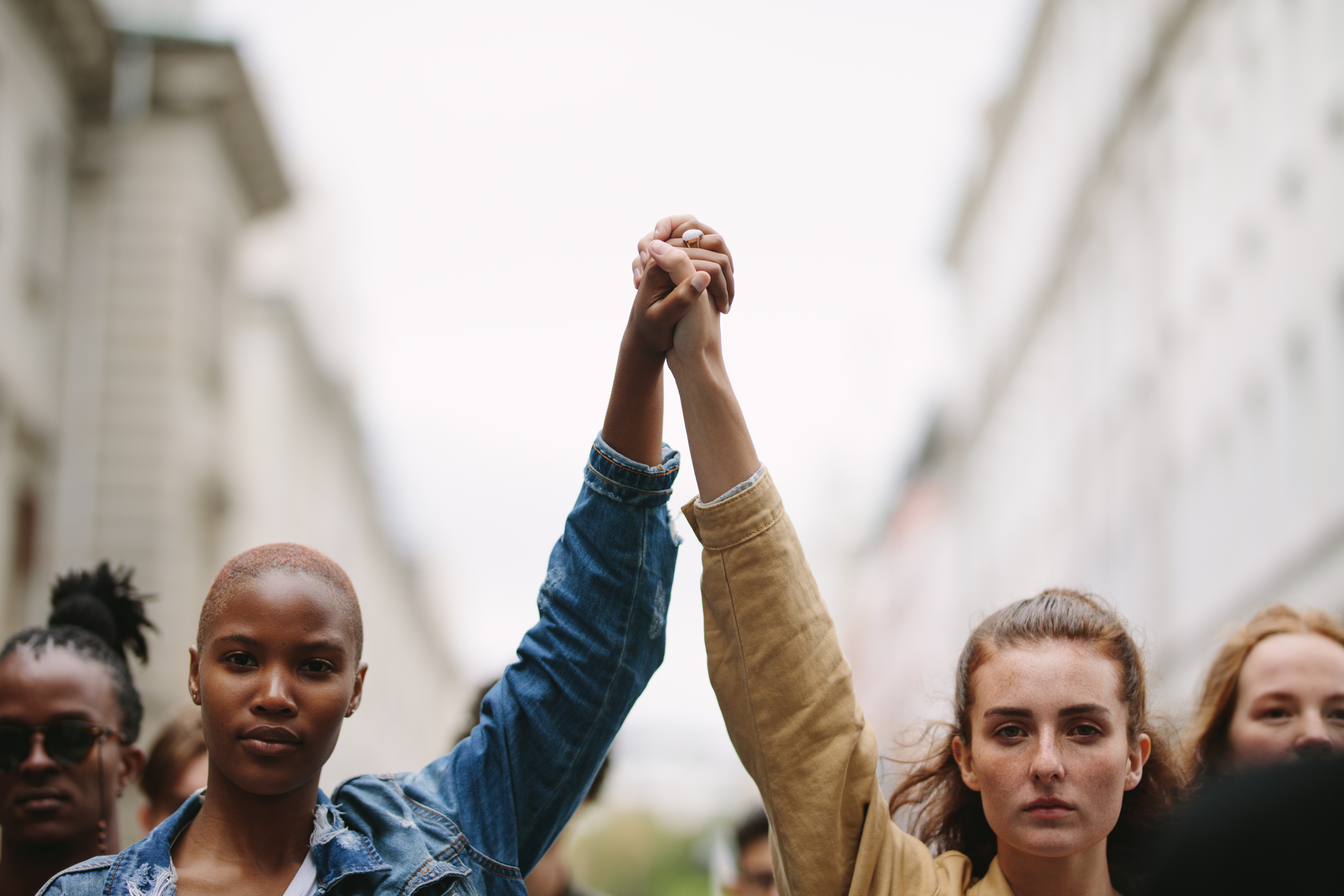 two woman holding hands showing unity in a protest