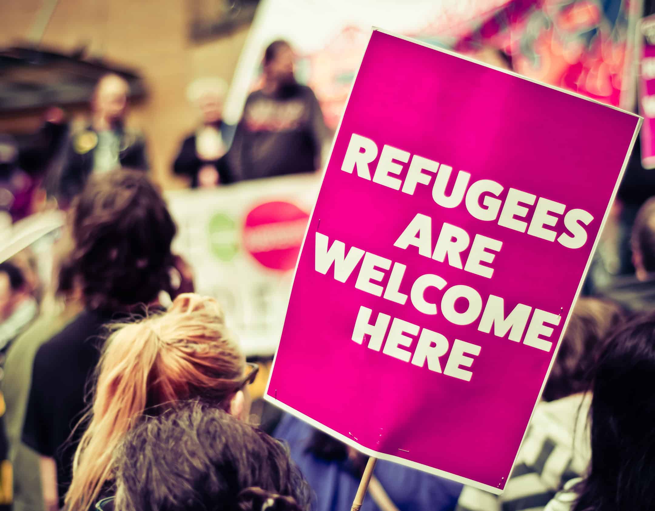 During a protest, a sign of "refugees are welcome here' is shown