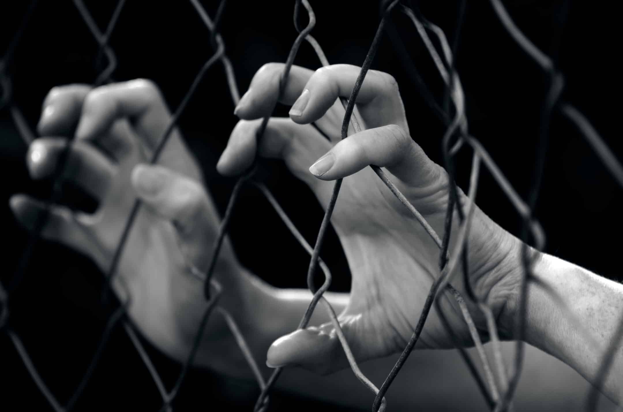 hands holding on to a cage cell