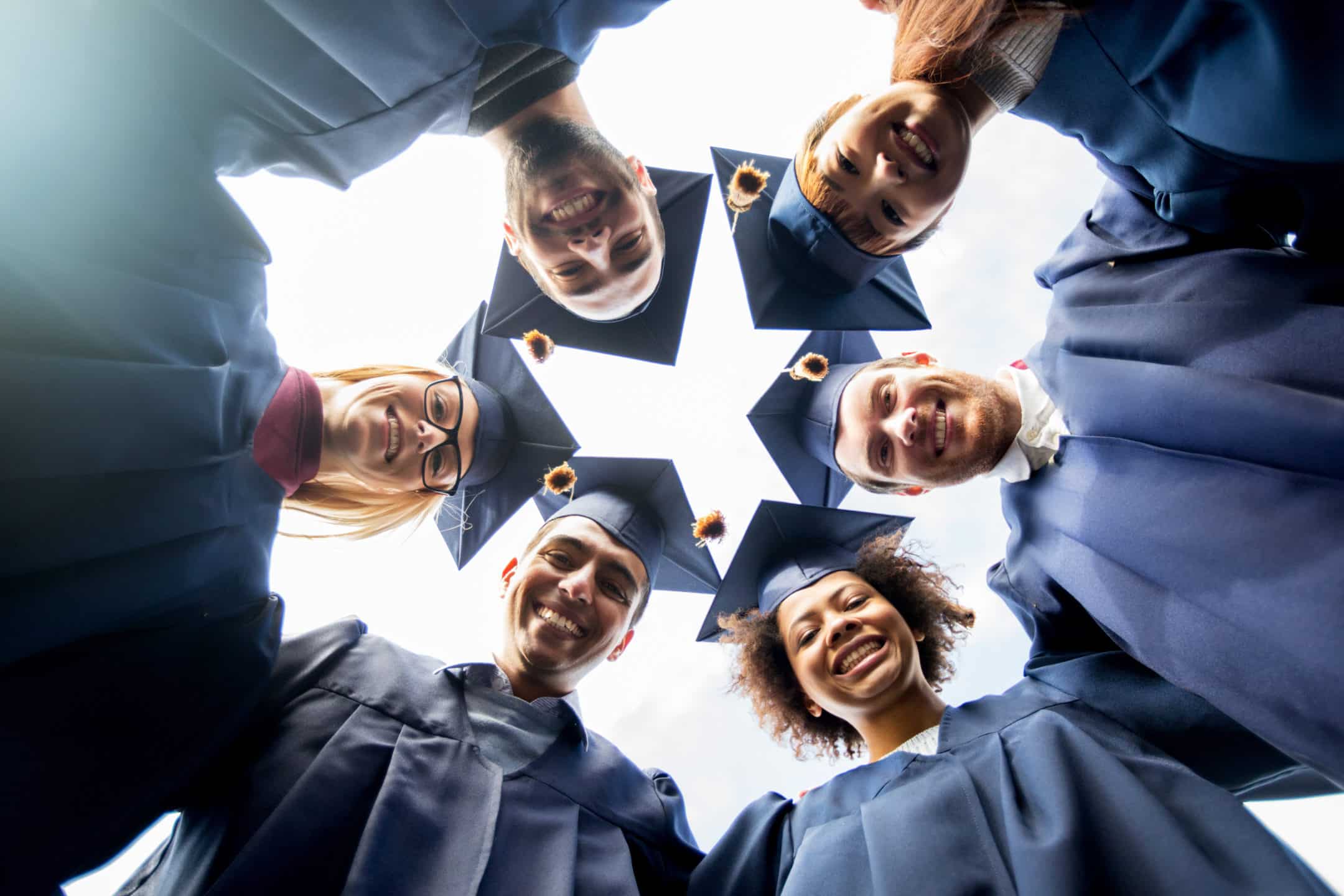 Group of graduating college students forming a circle and smiling