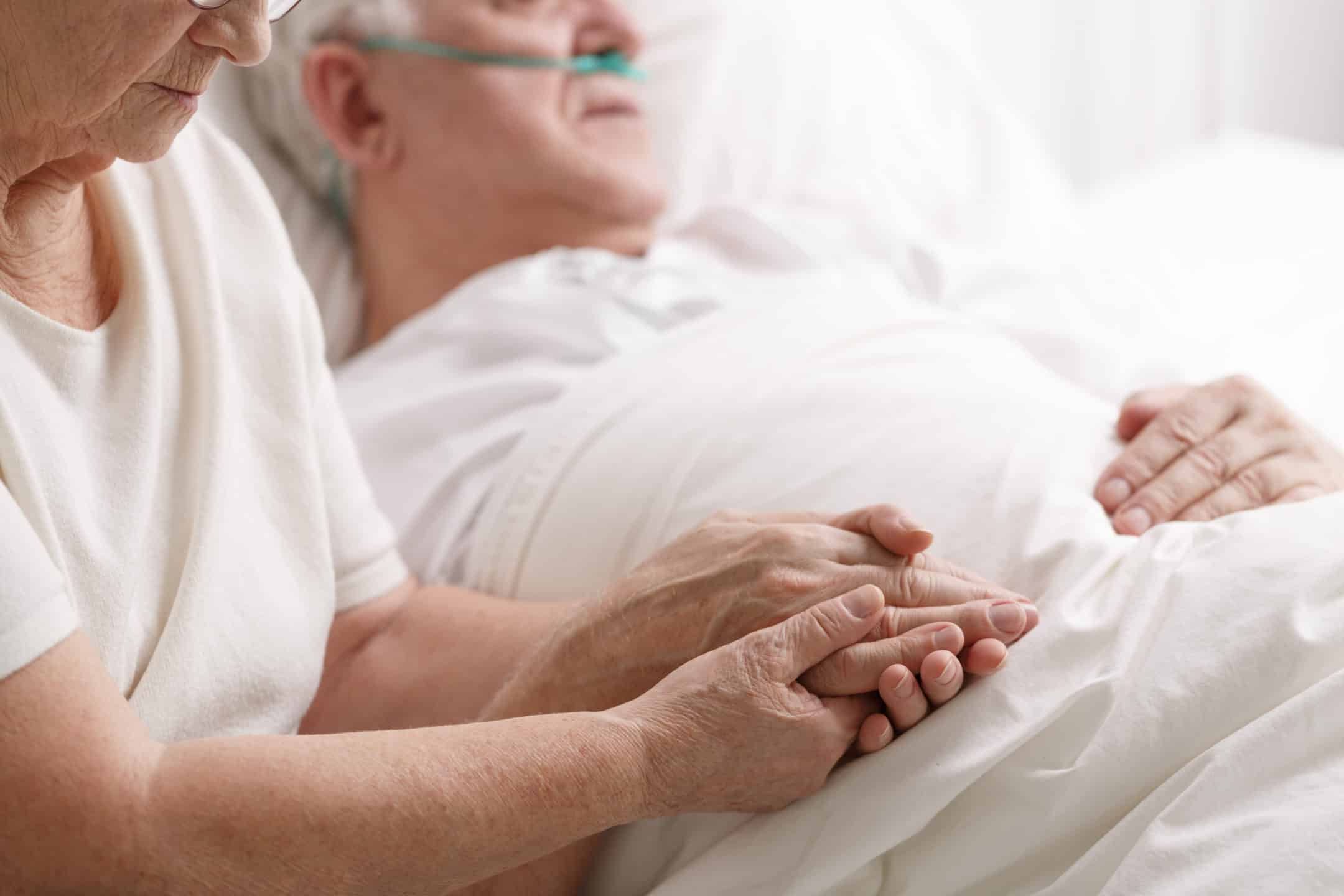 woman holding a senior's hand in the hospital