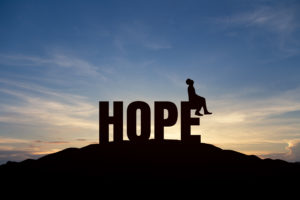 Silhouette of young man and the word "hope" on mountain