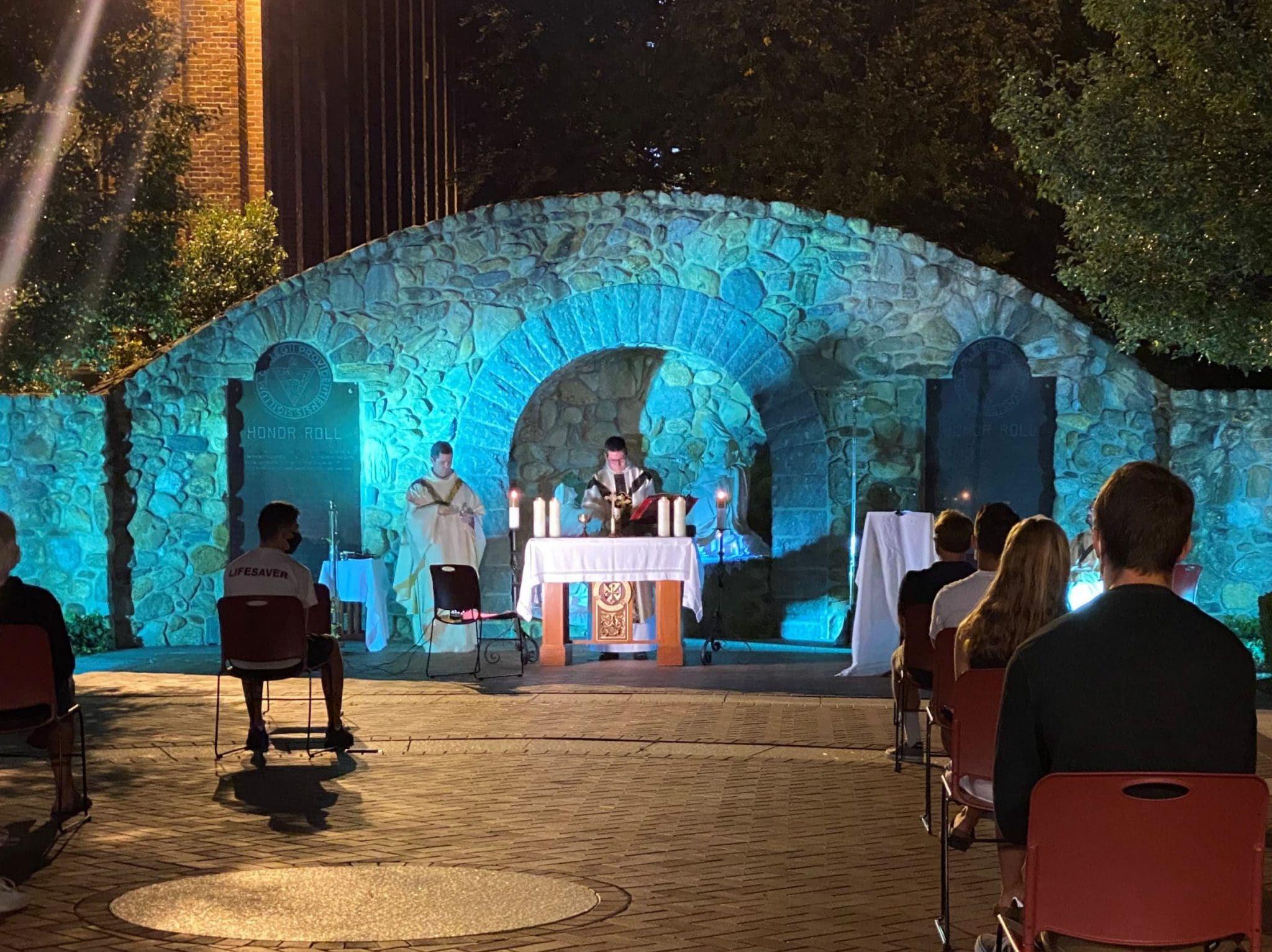 Father Briscoe and another priest celebrate outdoor Mass for students at Providence College's Rosary Grotto