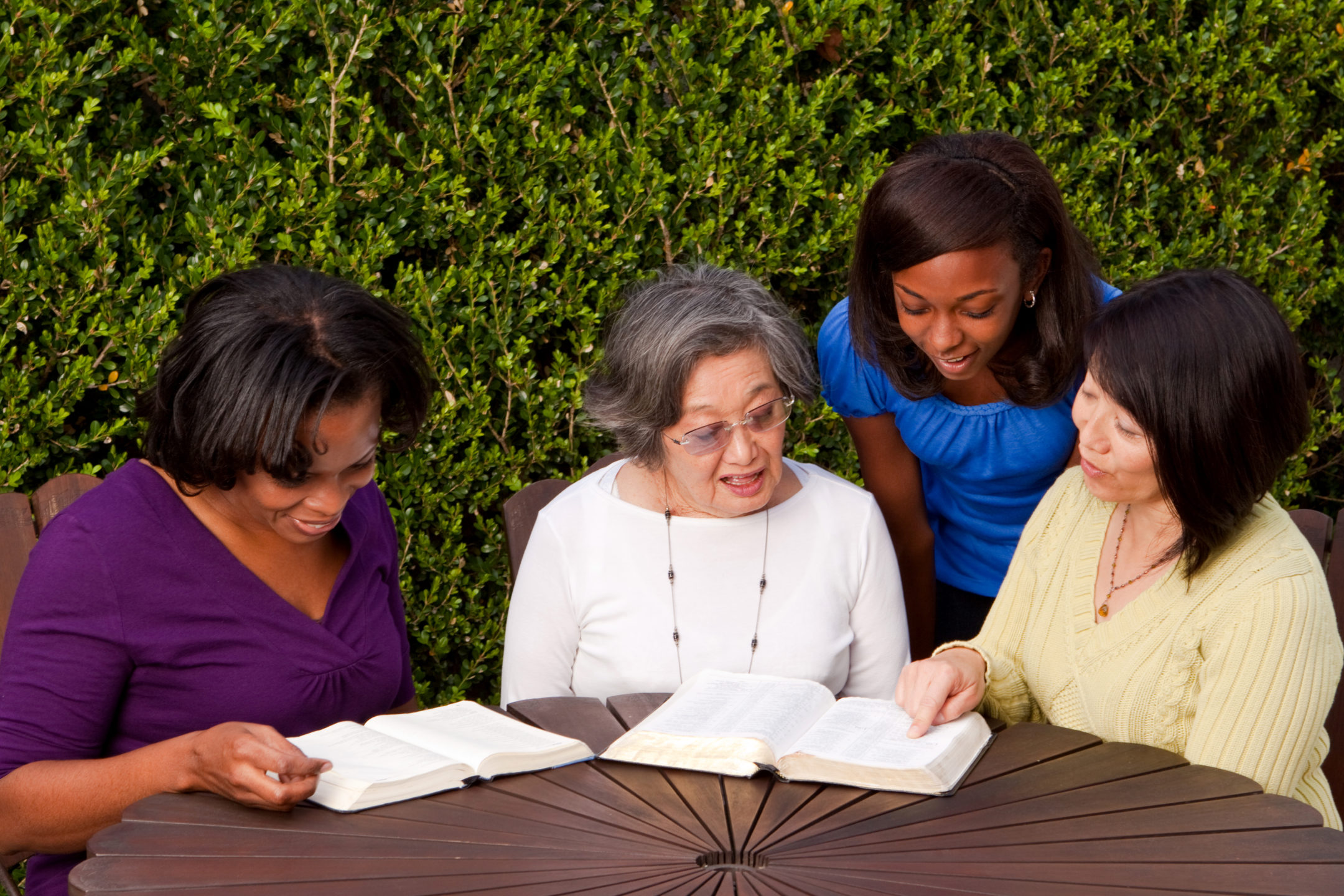 four multigenerational women sitting and reading together