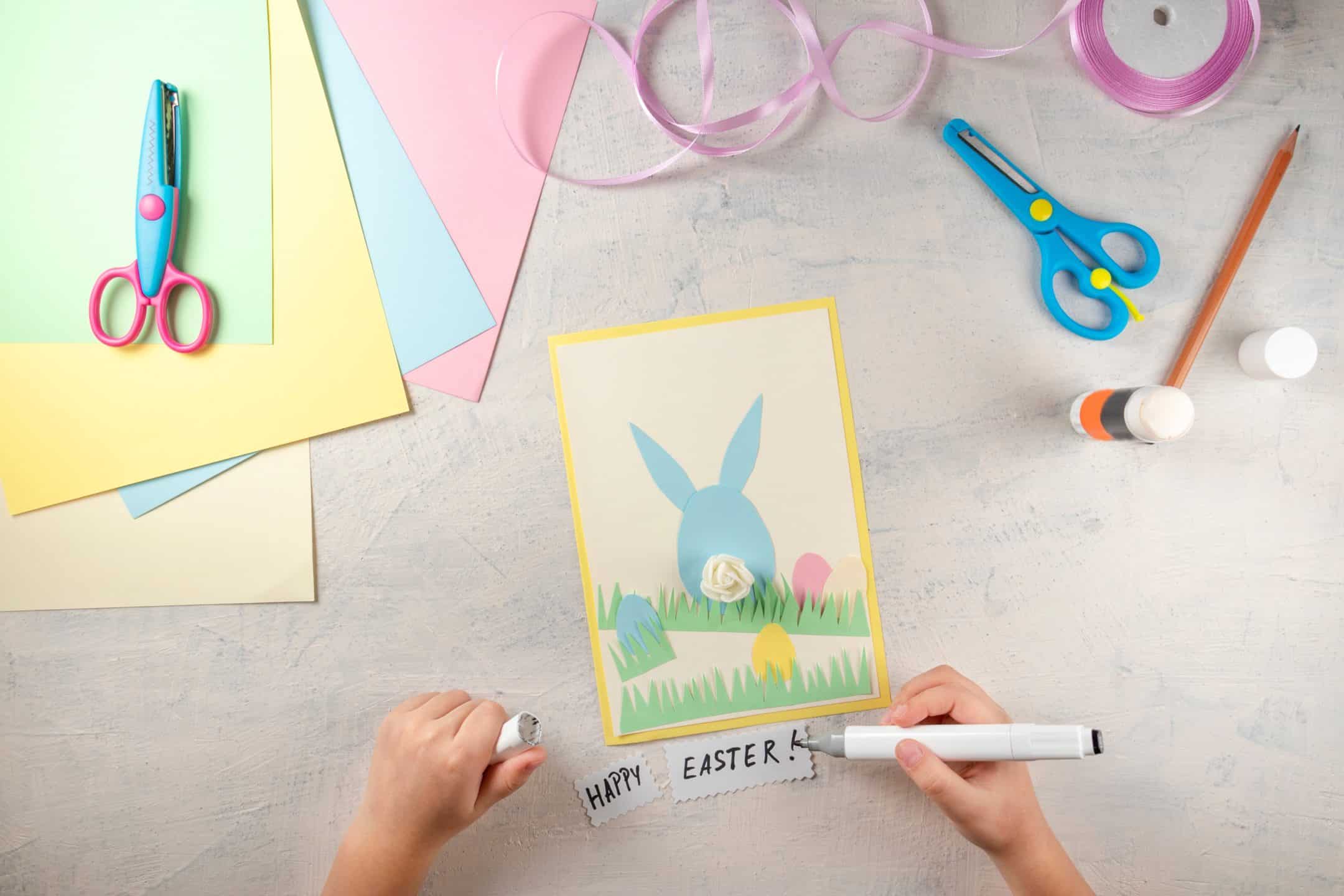 Child drawing, cutting Easter card