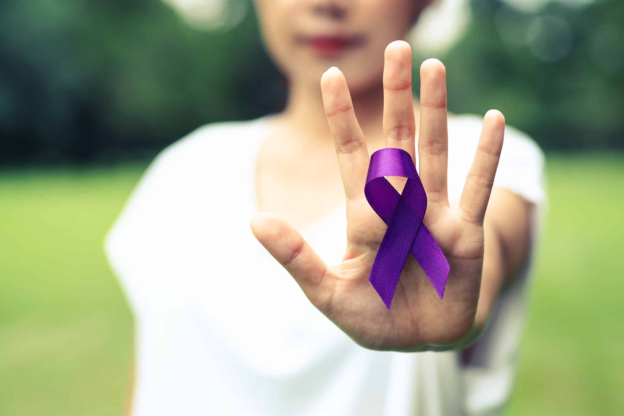 women with palm up holding a purple ribbon