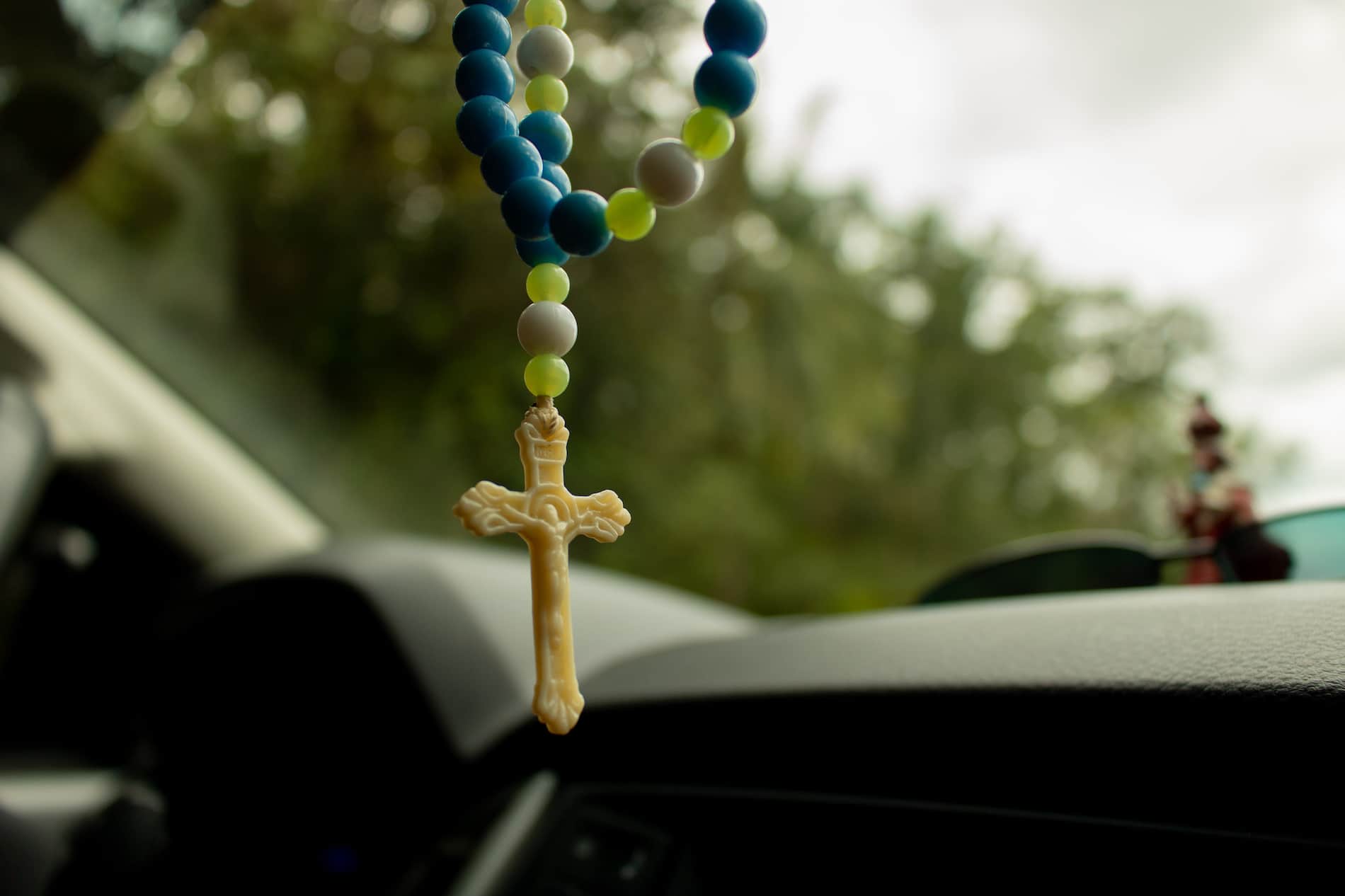 Close up image of Rosary beads hanging Inside a Car