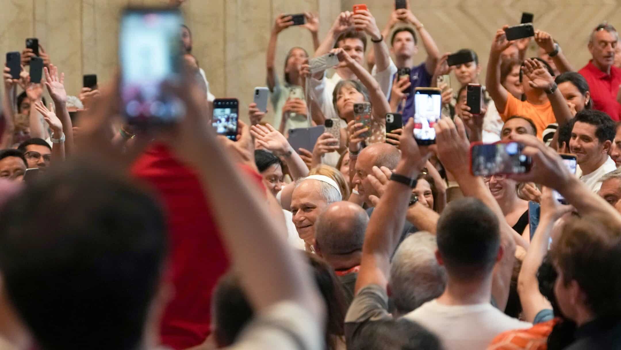 Crowd of people raising smartphones to take photos at an event.