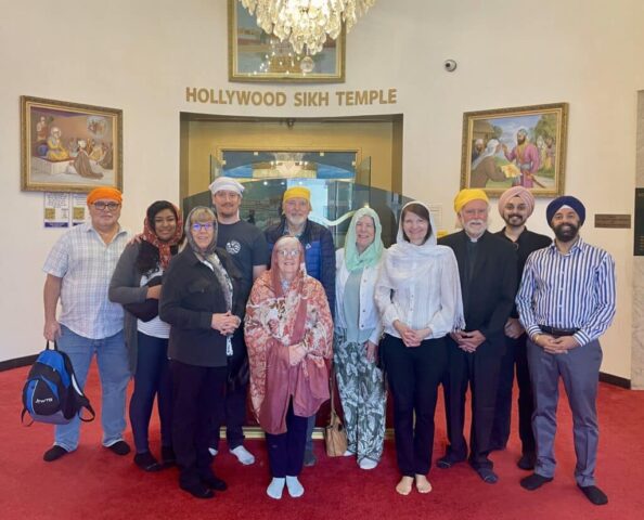 Group of diverse people wearing turbans posing for a photo inside the Hollywood Sikh Temple lobby.